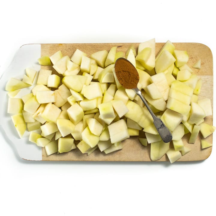 Chopped pears on a cutting board with a spoonful of spices on top. 