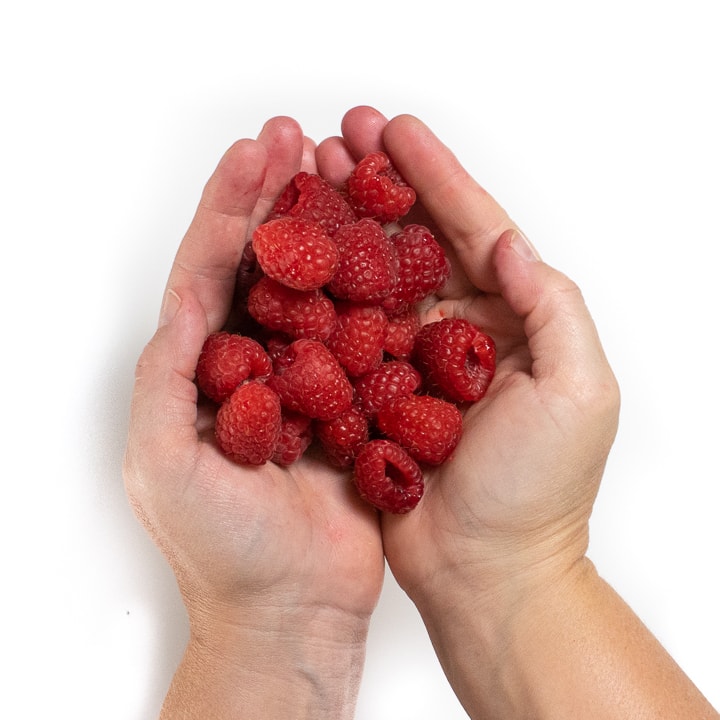 2 hands holding raspberries.