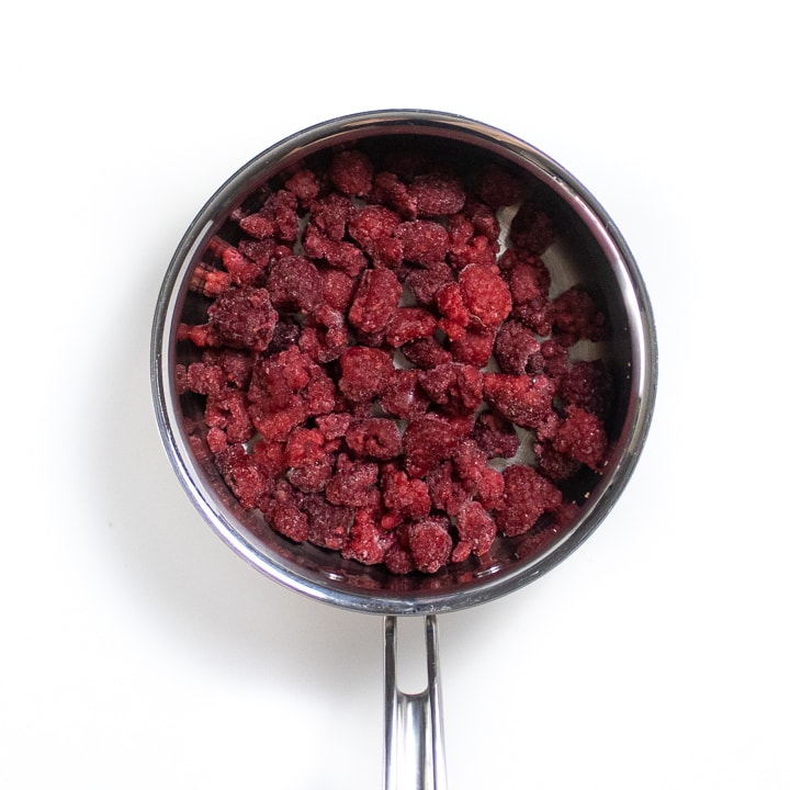 Sliver saucepan with frozen raspberries in it.