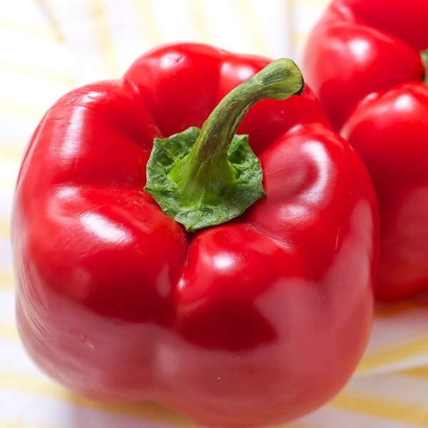 up close photo of a red pepper on top of a white and yellow napkin 