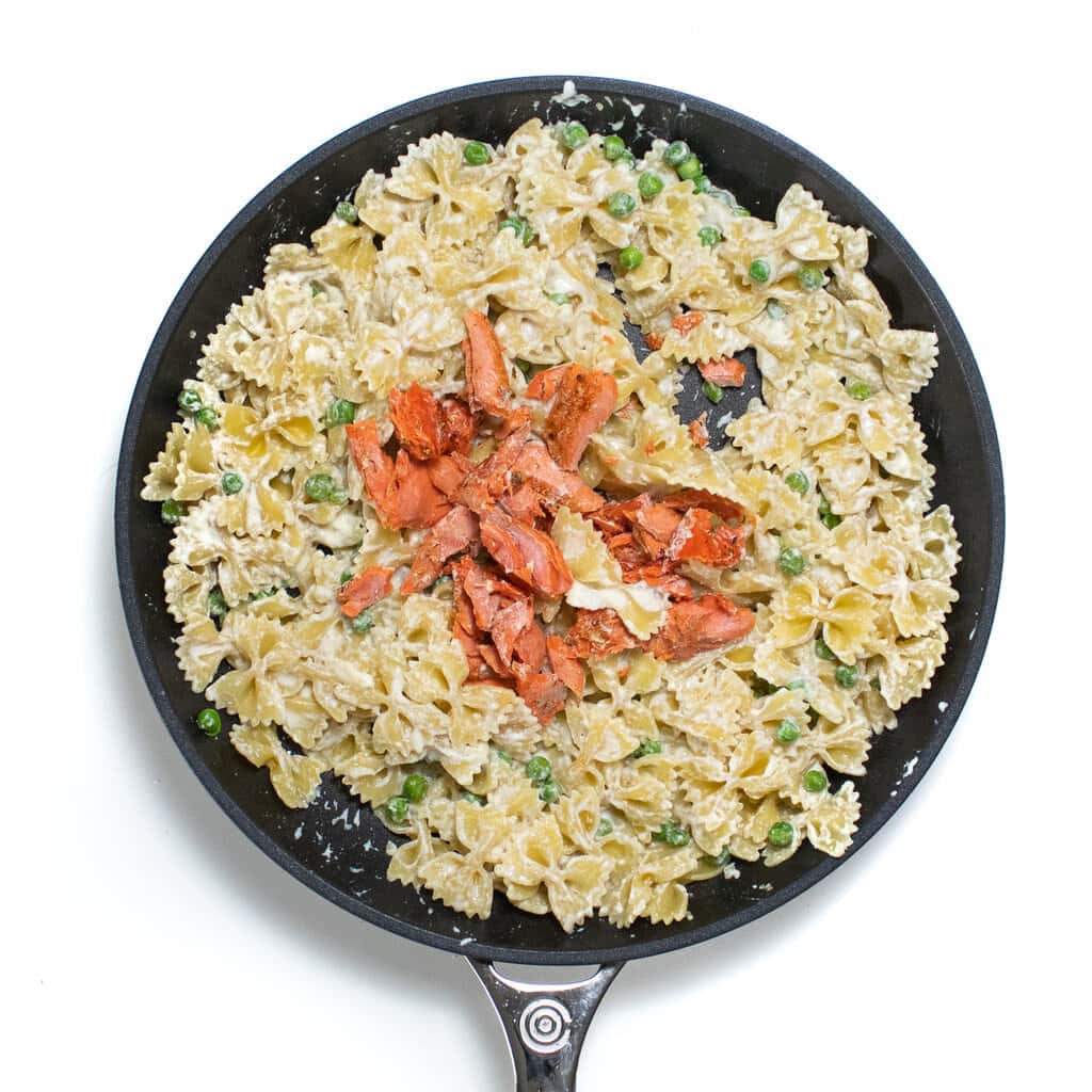 skillet filled with pasta, peas, salmon getting ready to mix together.