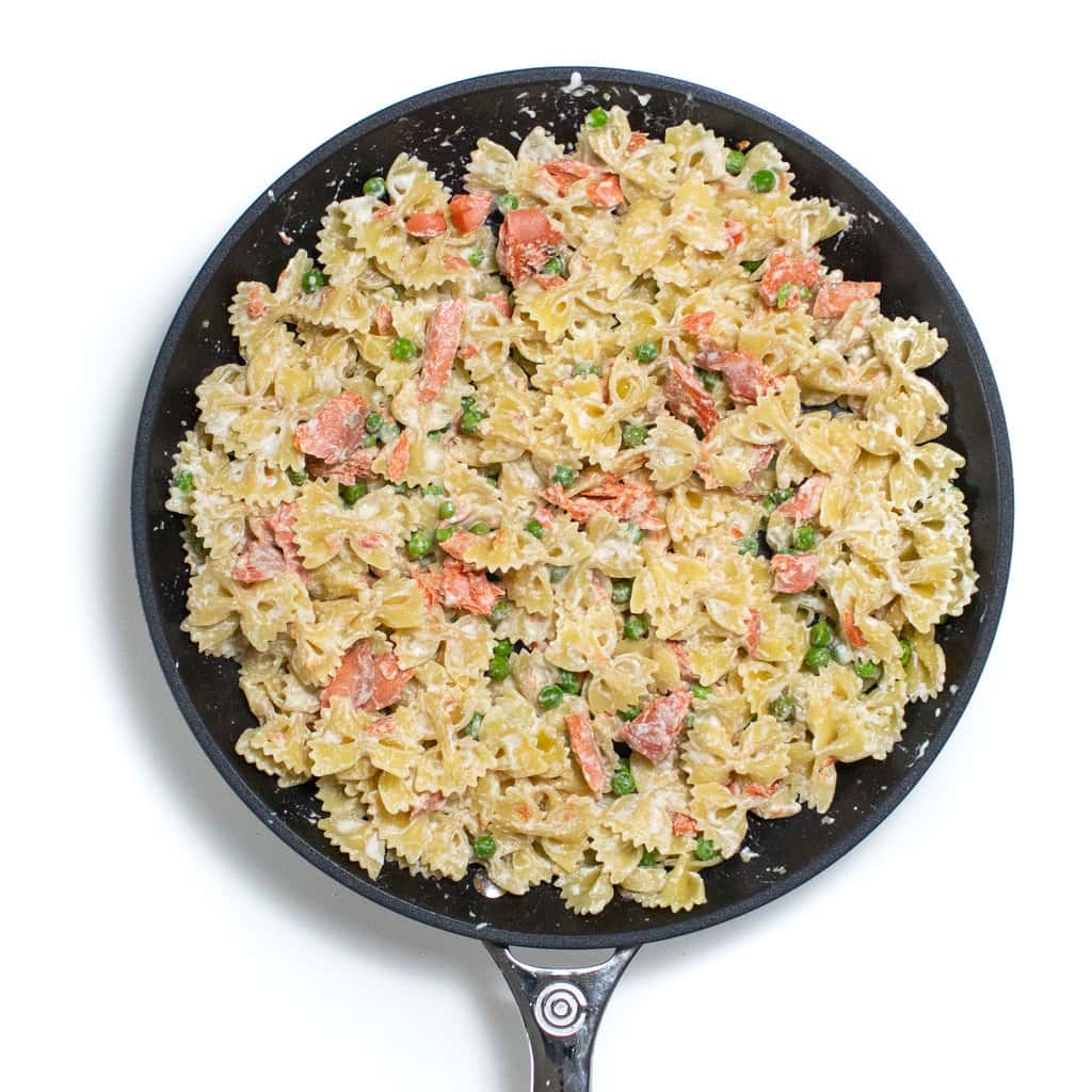 Skillet full of salmon, pasta, peas for a family dinner.