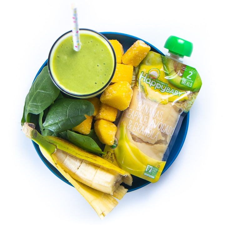 Green smoothie surrounded by a plate full of the healthy ingredients used to make it.