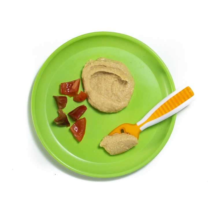 Plate with hummus and cut tomatoes for baby.