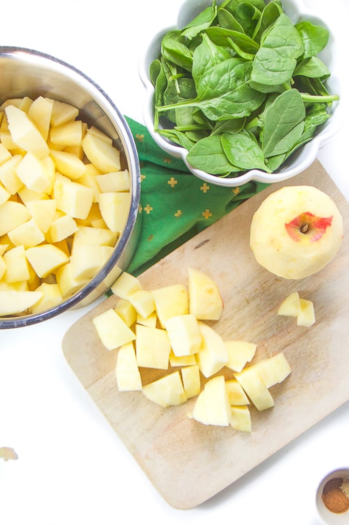 Cutting board with chopped apples with a saucepan next to it with more chunks of apple in it.