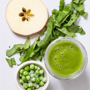 image of a white cutting board with produce scattered on it and a small bowl filled with the baby food puree.