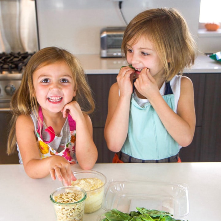 2 small girls getting ready to cook in the kitchen. 