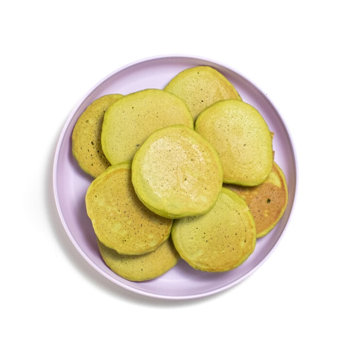 A purple toddler plate with a stack of spinach banana pancakes.