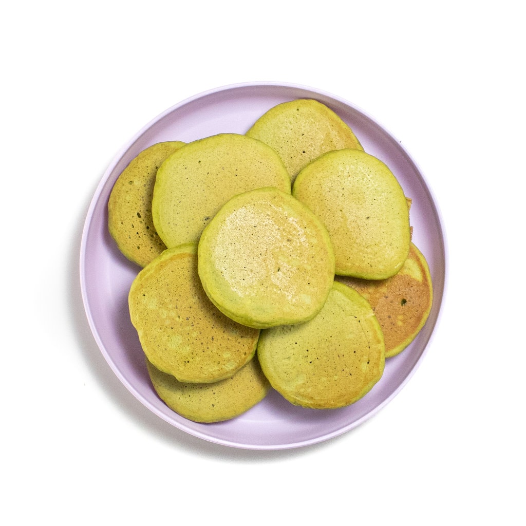 A purple toddler plate with a stack of spinach banana pancakes.