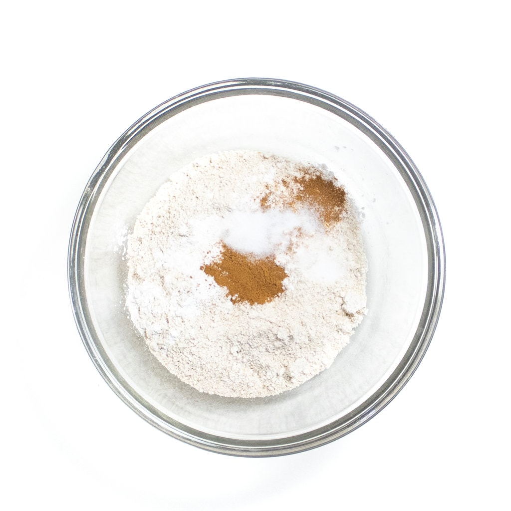 Clear glass mixing bowl filled with flour, cinnamon, baking soda and salt.