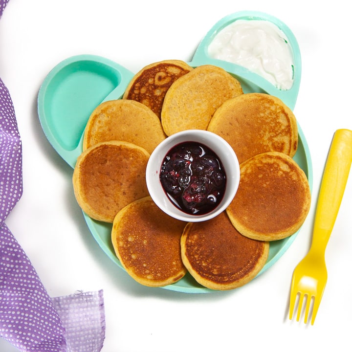 Plate full of sweet potato pancakes for baby with a fruit and yogurt dip.