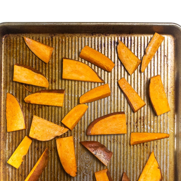 Baking sheet with raw sweet potatoes.