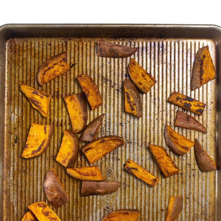 Sweet potato on a baking sheet, roasted in the oven.