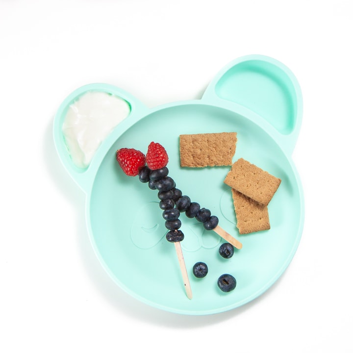 Toddler plate with berries, crackers and dip.