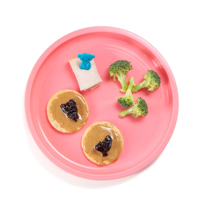 Toddler or kid snack of pb&j crackers, cut broccoli and rolled up turkey.