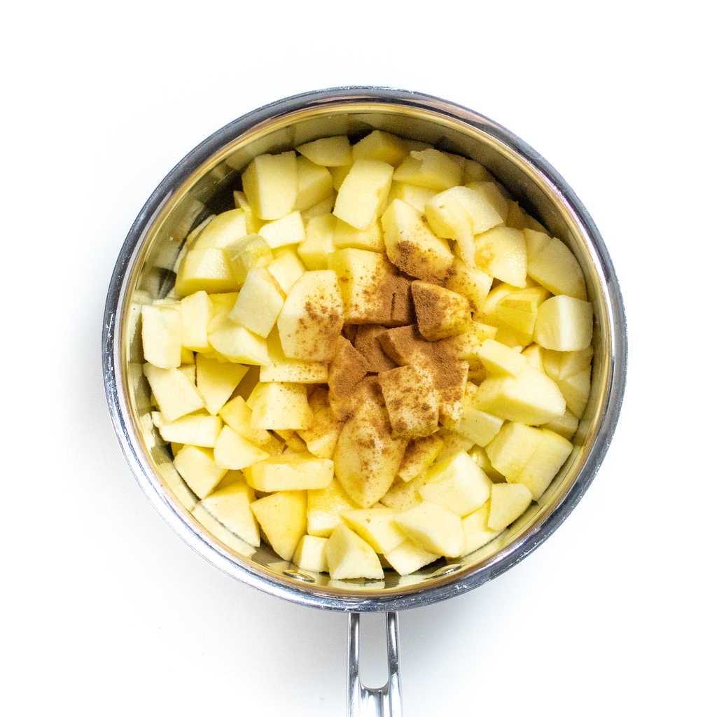 Silver saucepan with chunks of apples, cinnamon and vanilla.