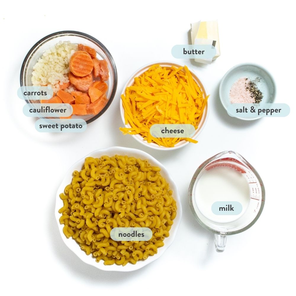 Spread of ingredients for a recipe of veggie mac & cheese, all ingredients have fonts with their titles and accident on a white countertop.