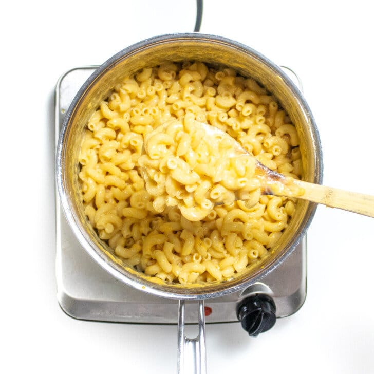 A silver sauce pan with mixed noodles in a veggie cheese sauce.