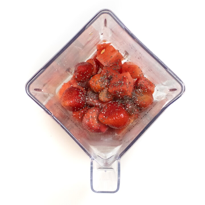 Clear blender on a white background with watermelon frozen strawberries, Chia seeds and my juice.