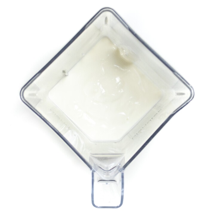 A clear blender with yogurt inside.