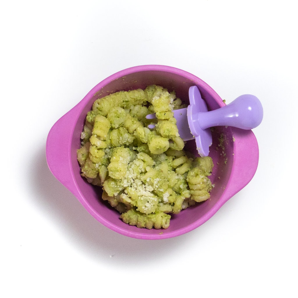 A pink baby bowl with a chunky zucchini pasta stage three meal for Baby.