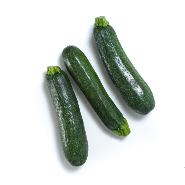 Three zucchini sitting on a white background.